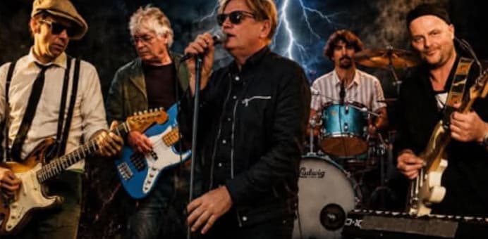 The Thunder Fabulous against a dark sky with lightning: the singer in sunglasses and a black shirt at the microphone in the middle, a guitarist in a flat cap and braces on the left, a bassist with a blue bass, the drummer behind and a guitarist in a beanie on the right.